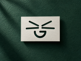 Logo-Design für Grinsekatze – minimalistisches Katzenlogo als ausgestanztes Motiv auf cremefarbenem Karton vor dunkelgrünem Hintergrund mit natürlicher Papierstruktur und weichem Schatten
